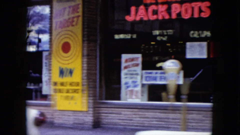 Red jackpot lettering and a yellow target-game sign appear on a Nevada storefront in this 1959 nighttime street view.