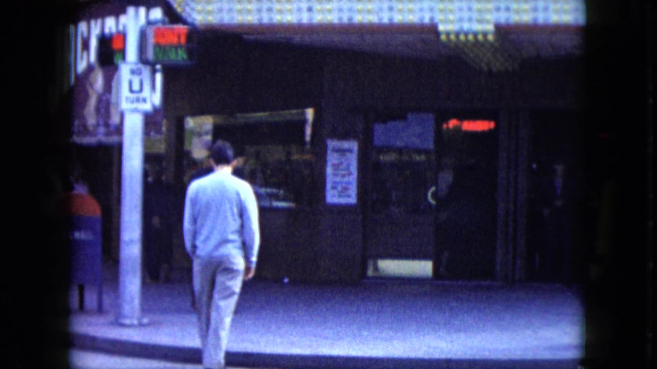 Man seen from behind near a gambling hall entrance and street signs.