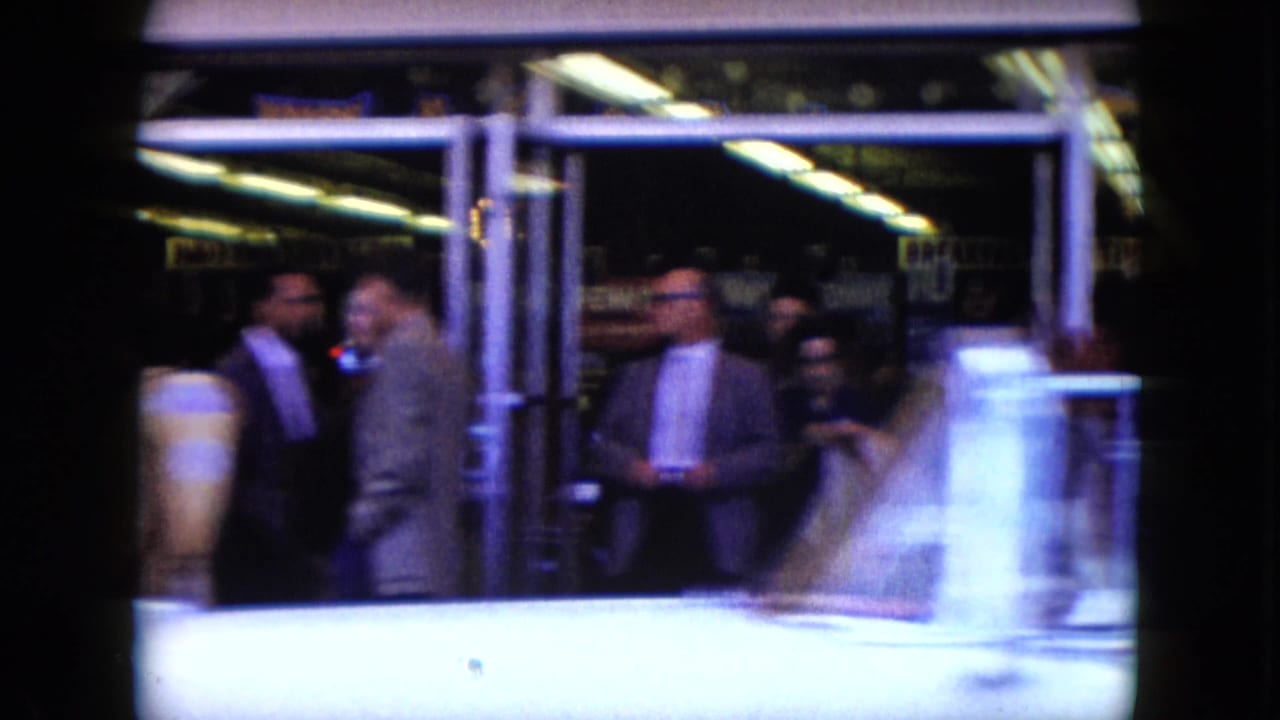 1959 Nevada street footage shows several adults near a glass-fronted entrance during a handheld pan.