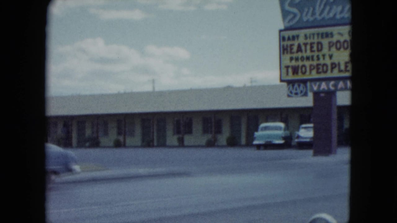 1959 Nevada frame showing a low motel building, parked cars, open roadside pavement, and the cropped Salinda Motel sign at right.