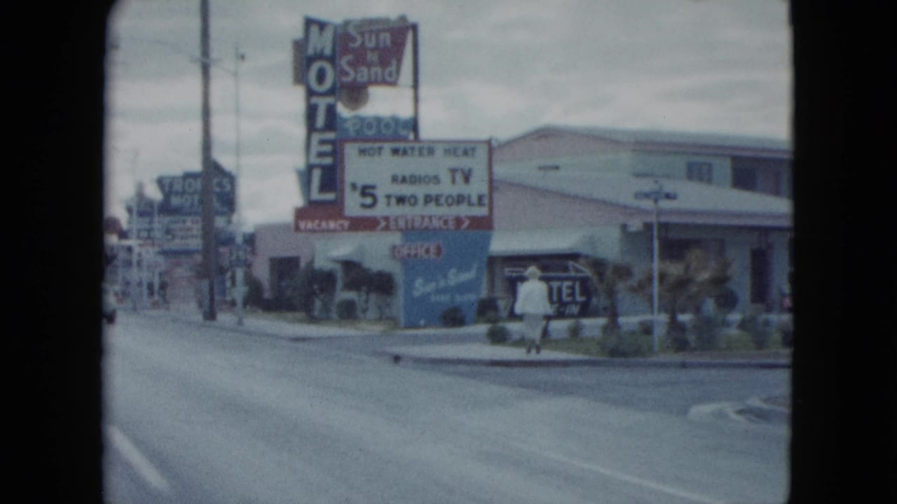 Motel entrance area with rate signage and a person walking near the sidewalk.