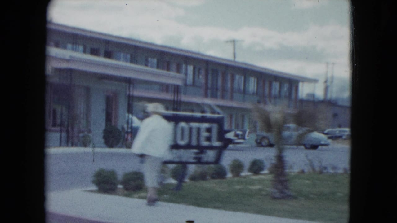 Woman walking near a motel sign and mid-century motor lodge.