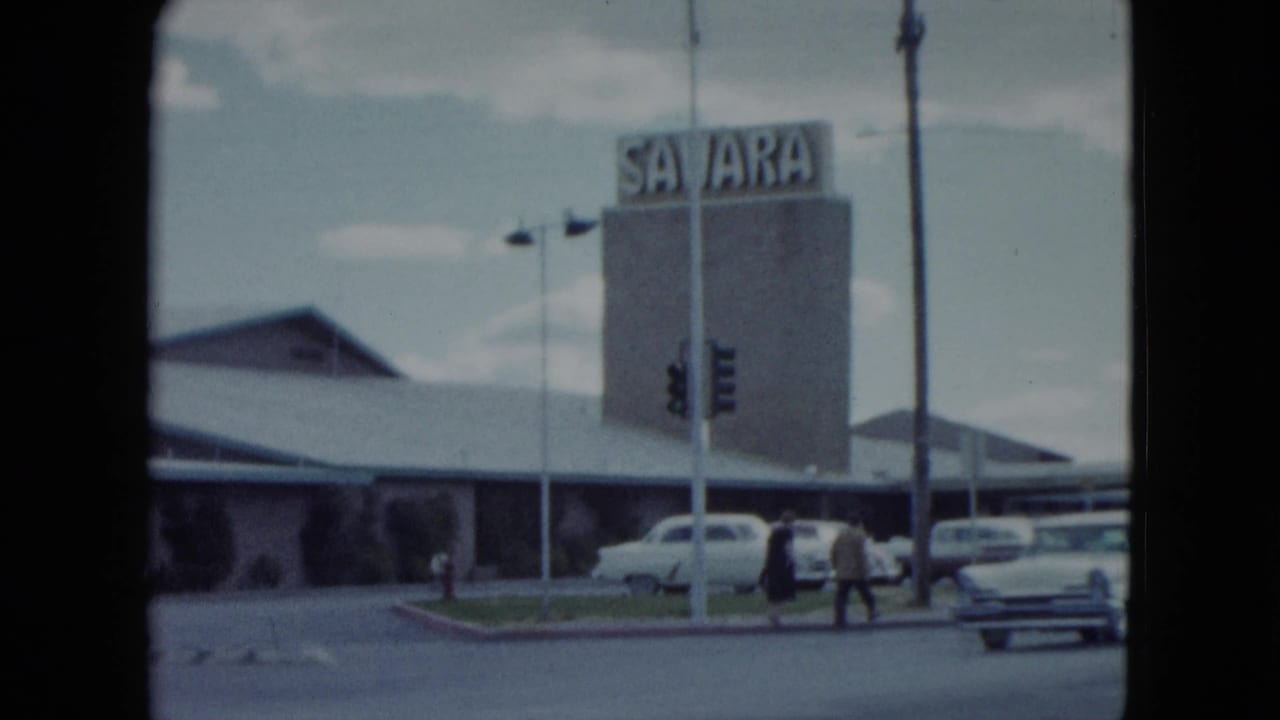 1959 Nevada frame with the Sahara sign, hotel frontage, pedestrians, traffic lights, and parked cars.