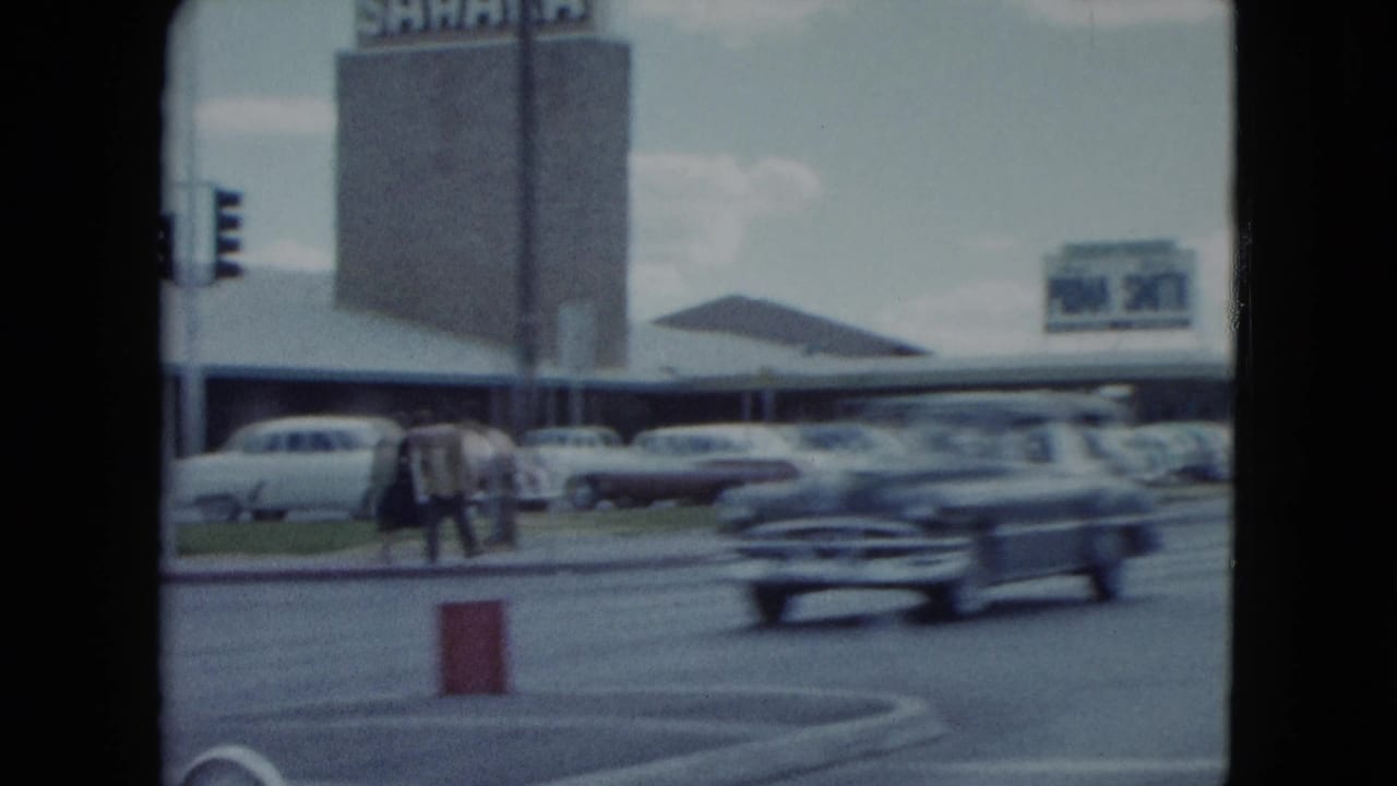 Nevada 1959 home-movie view of the Sahara frontage, pedestrians, parked cars, and a passing classic car.