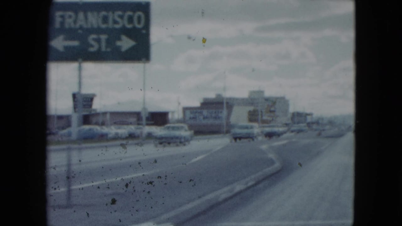 San Francisco St. road sign fills the foreground, with late-1950s traffic and commercial buildings beyond in Nevada.