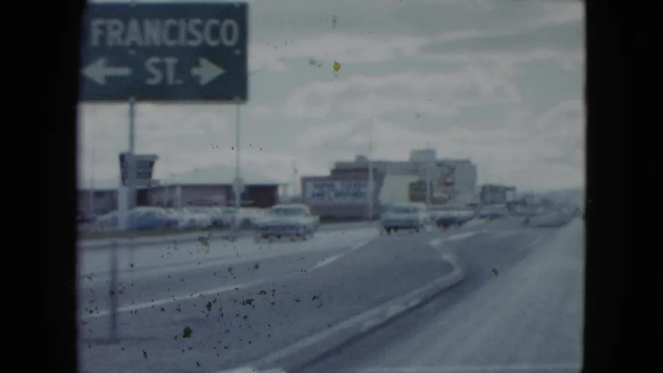 San Francisco St. road sign fills the foreground, with late-1950s traffic and commercial buildings beyond in Nevada.