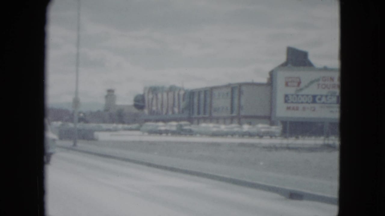 1959 Nevada roadside view with a large prize-tournament sign, parked cars, and commercial structures.