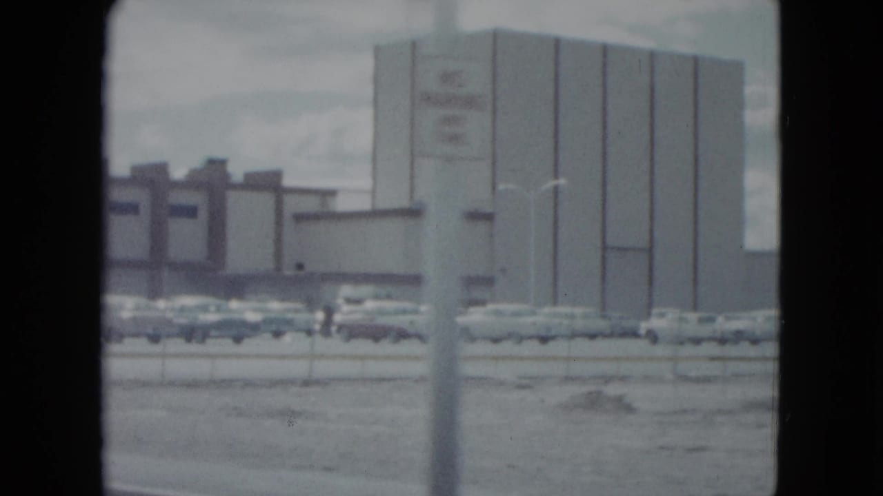 1959 Nevada street view of a large commercial building, parking area, cars, and a roadside pole.