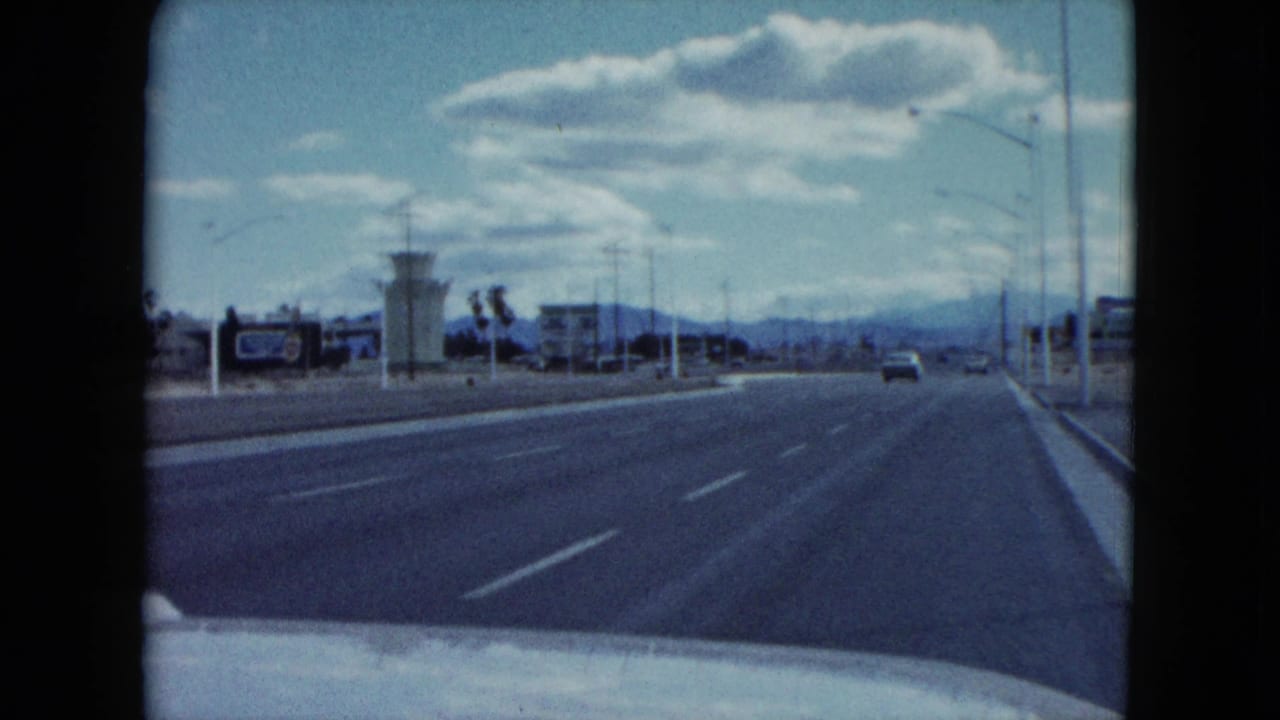 Wide Nevada highway seen from a moving car under a blue sky with clouds.