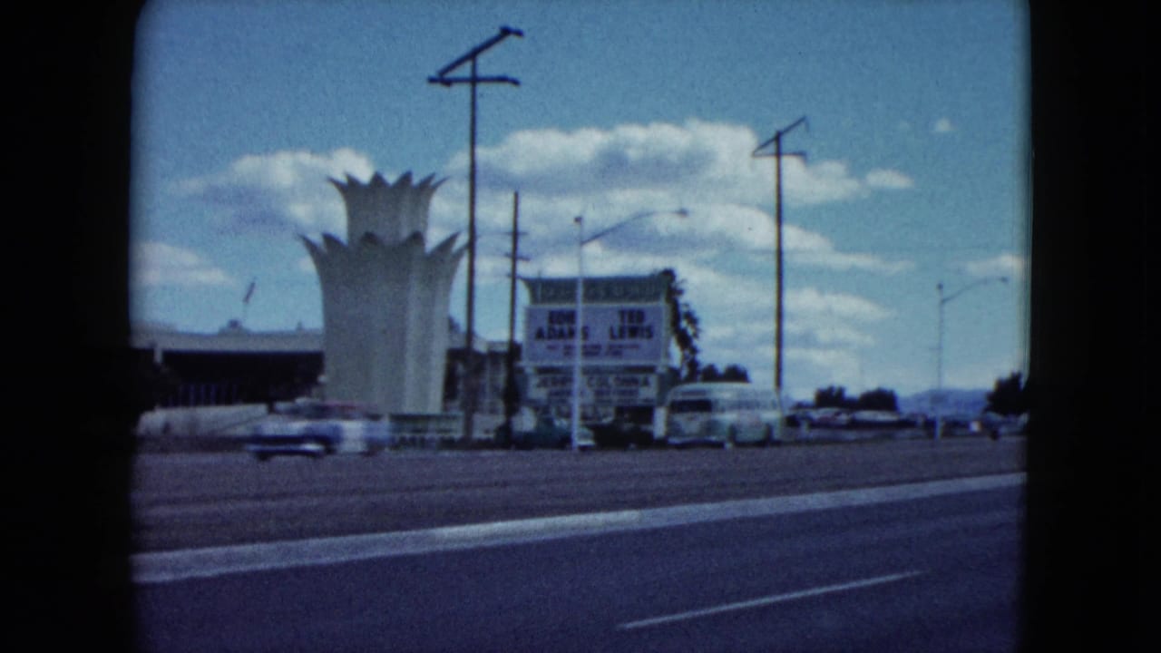 White crown-shaped roadside structure beside a road with cars and signs.