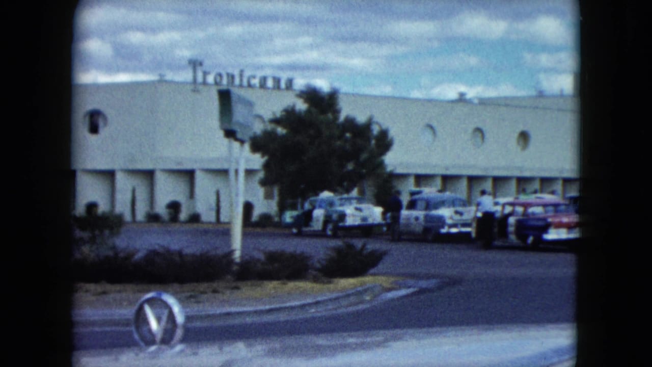 1959 Nevada home-movie frame showing a Tropicana exterior, parked late-1950s cars, rounded frame edges, and a roadside foreground.