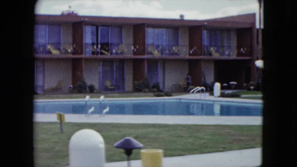A quiet Nevada poolside courtyard appears in 8mm footage, with balcony rooms, lawn, pool ladder, and outdoor fixtures.