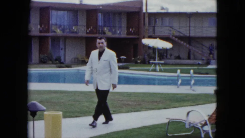 The final frame shows the man passing poolside furniture as the motel courtyard and pool remain visible.