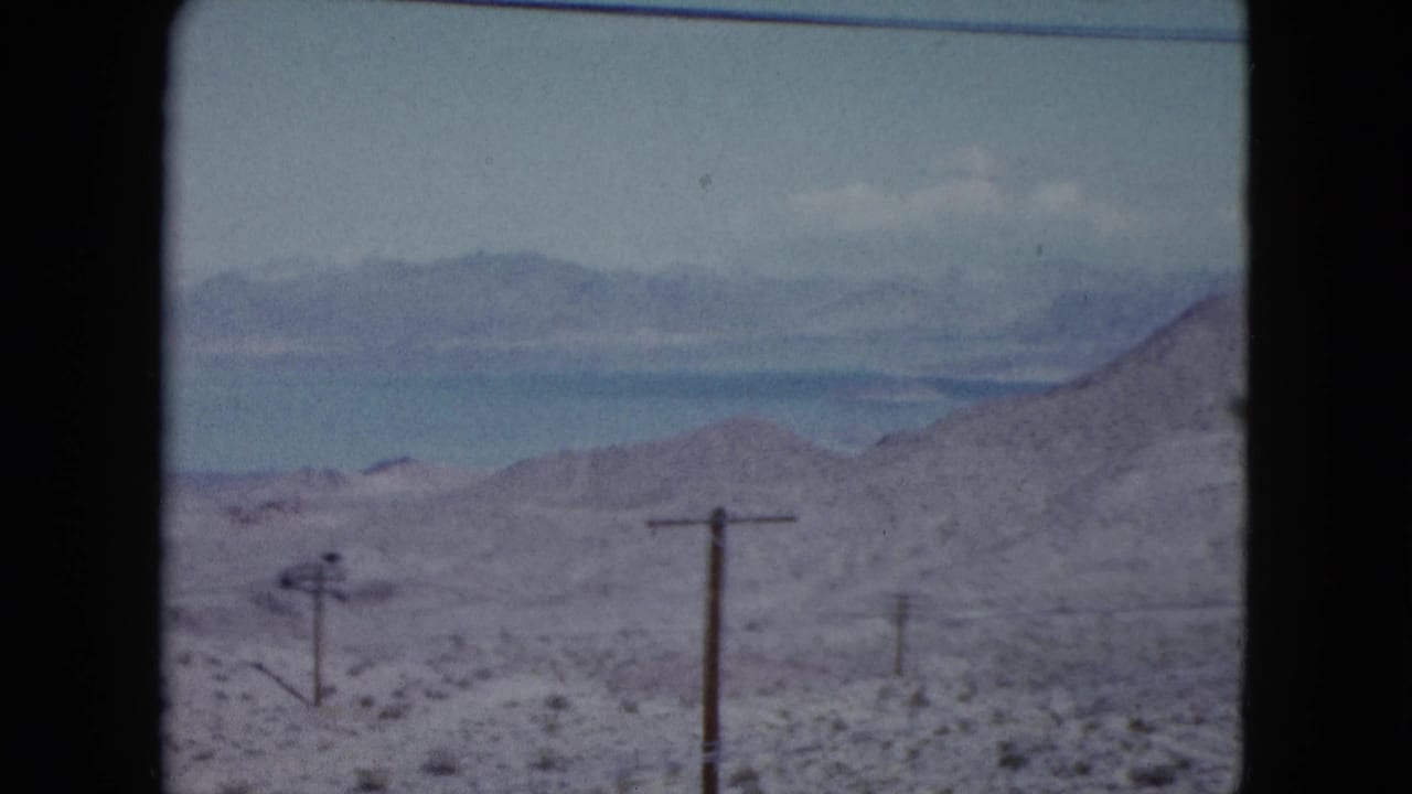Mid-century Nevada desert footage showing telephone poles in open brushland with hazy mountains beyond.