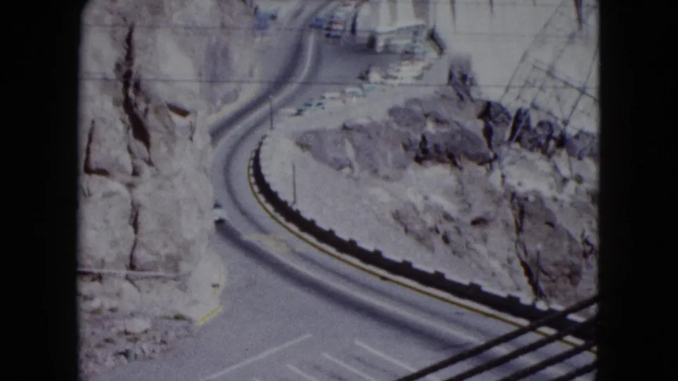 1959 Nevada 8mm frame showing a winding approach road through rocky terrain near Hoover Dam.