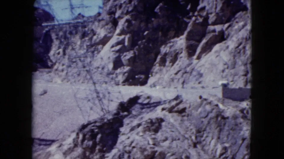 A wider 1959 Nevada 8mm view looks along the rocky canyon near the dam, with concrete edges visible at the side.