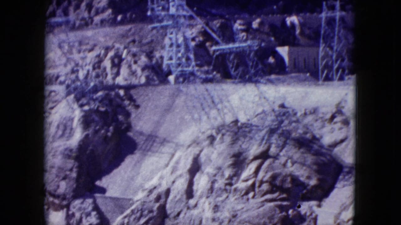 1959 Nevada footage showing power lines and utility towers set against rugged rock formations and dry ground.