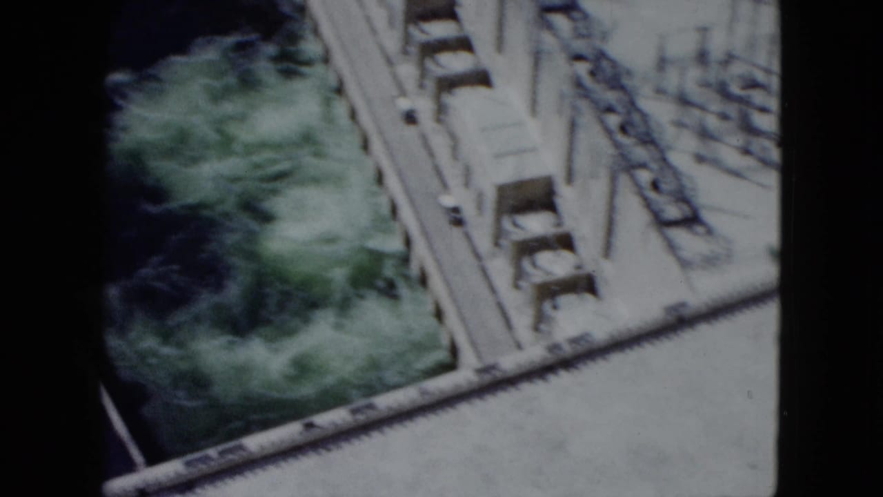 High-angle 1959 Nevada dam view with concrete infrastructure bordering fast-moving green water below.