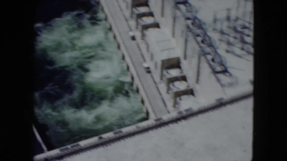 High-angle 1959 Nevada dam view with concrete infrastructure bordering fast-moving green water below.