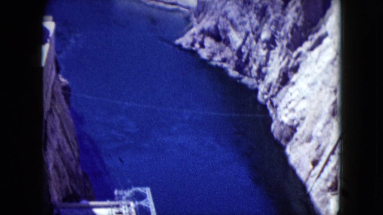 Blue river below steep canyon walls with concrete structure at the lower edge.