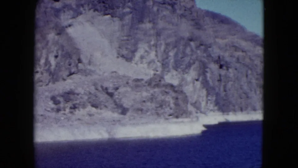 1959 Nevada home-movie view of rugged cliffs meeting a blue body of water under clear sky.