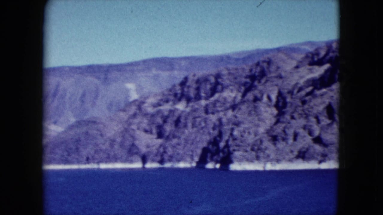 Rocky cliffs above deep blue water under a pale sky.