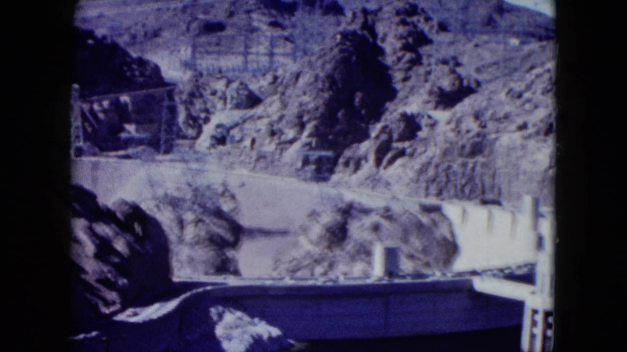 1959 Nevada view of Hoover Dam from across the water, with rocky canyon terrain and concrete dam details visible.