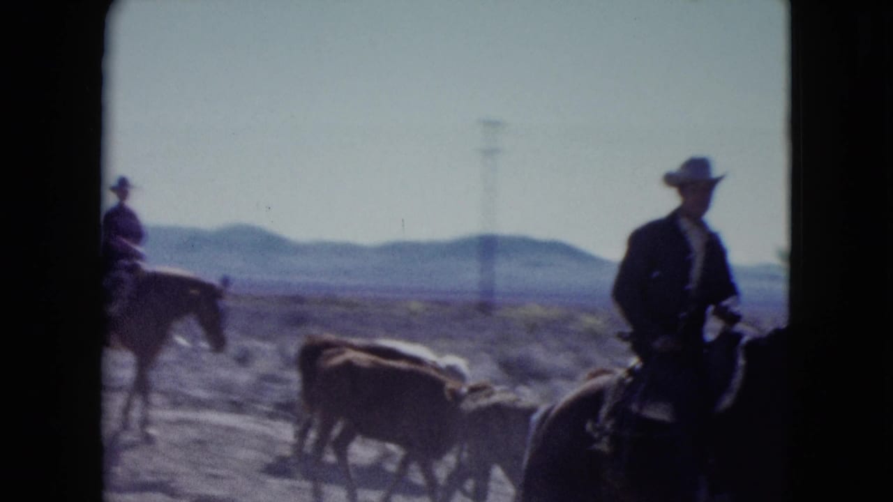 1959 Nevada 8mm frame showing horseback riders in cowboy hats with cattle in a dry open landscape and distant hills.