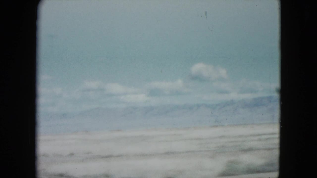 Pale desert plain with distant mountains under a blue sky.