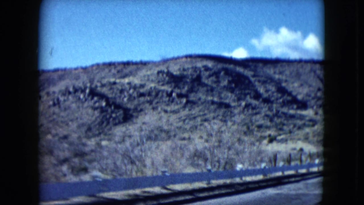 Nevada desert hills and sparse roadside vegetation fill the frame, with the road edge visible at the bottom of the 8mm shot.