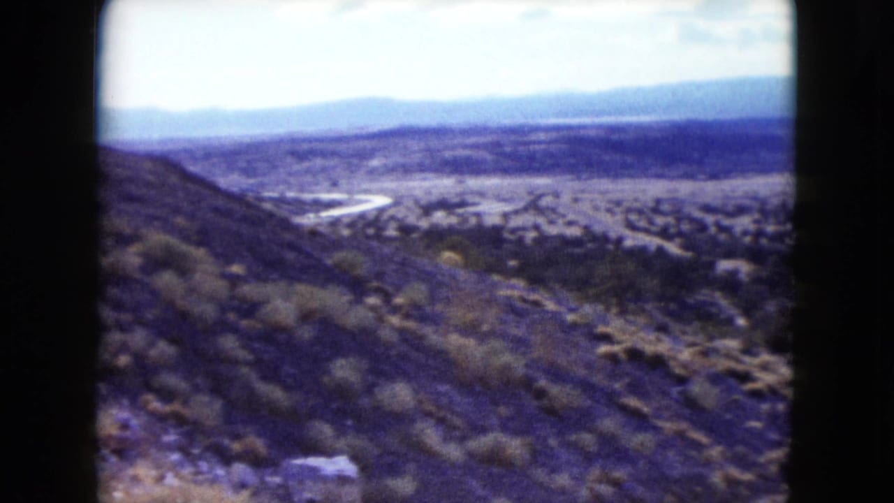 Dry hillside overlooking a valley with a pale winding road or wash below.