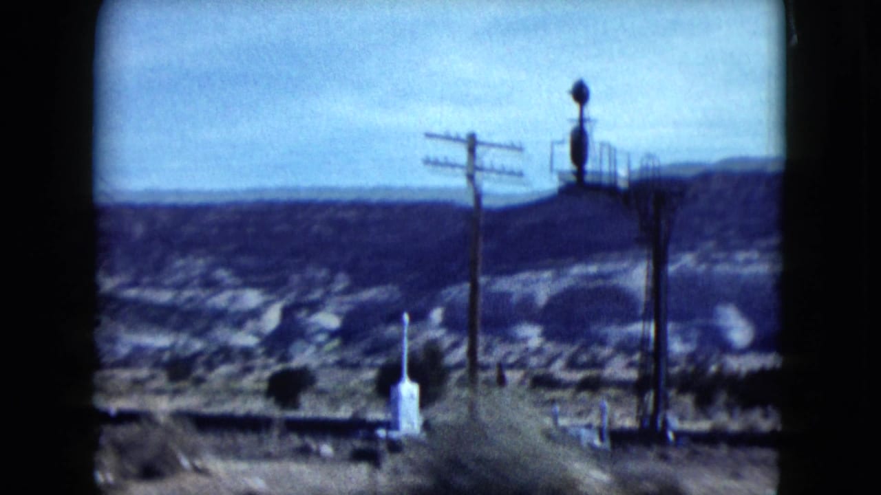 Roadside utility poles and a small pale roadside marker against canyon terrain.