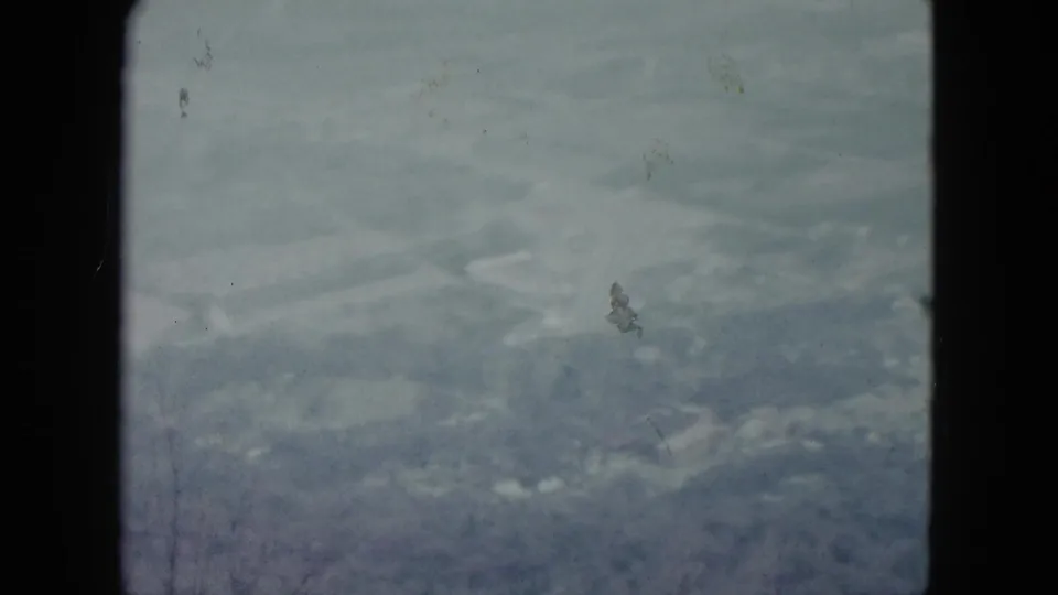 1959 Nevada home-movie frame of a misty valley with reservoir-like pale shapes, distant terrain, dust marks, and dark 8mm gate edges.
