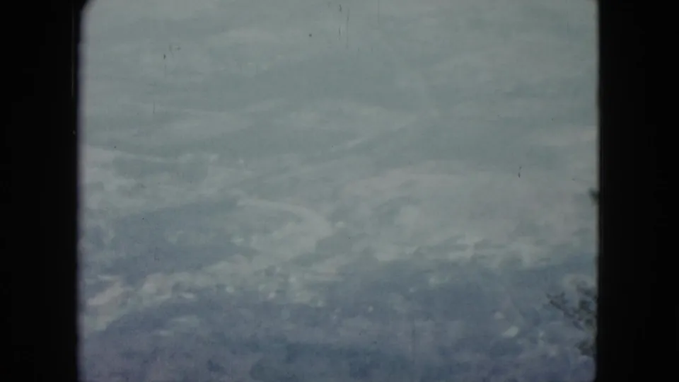 Nevada 8mm home-movie still showing a blurred aerial farmland view with cloudy sky and window framing.