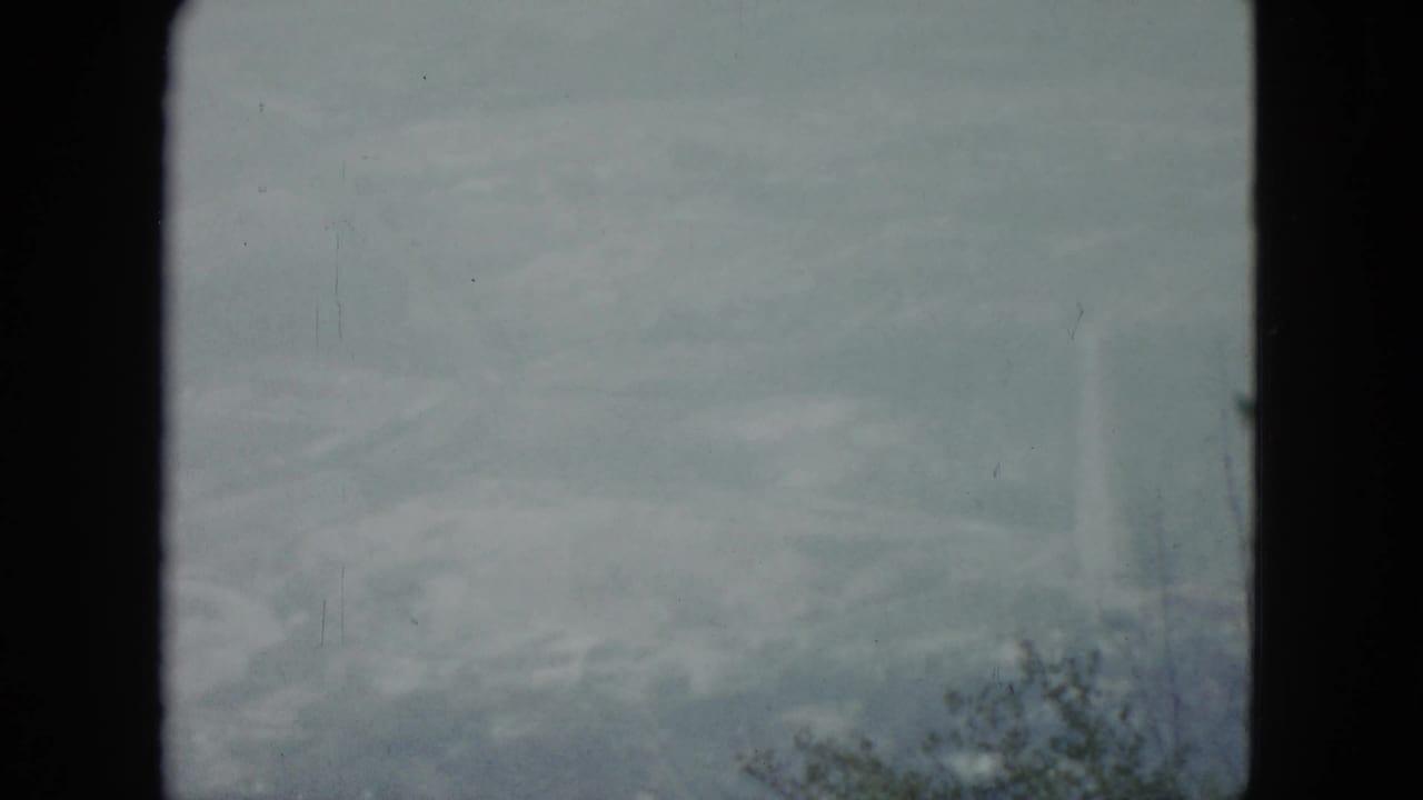 Hazy pale sky over a distant ridge with scrub vegetation along the lower edge.