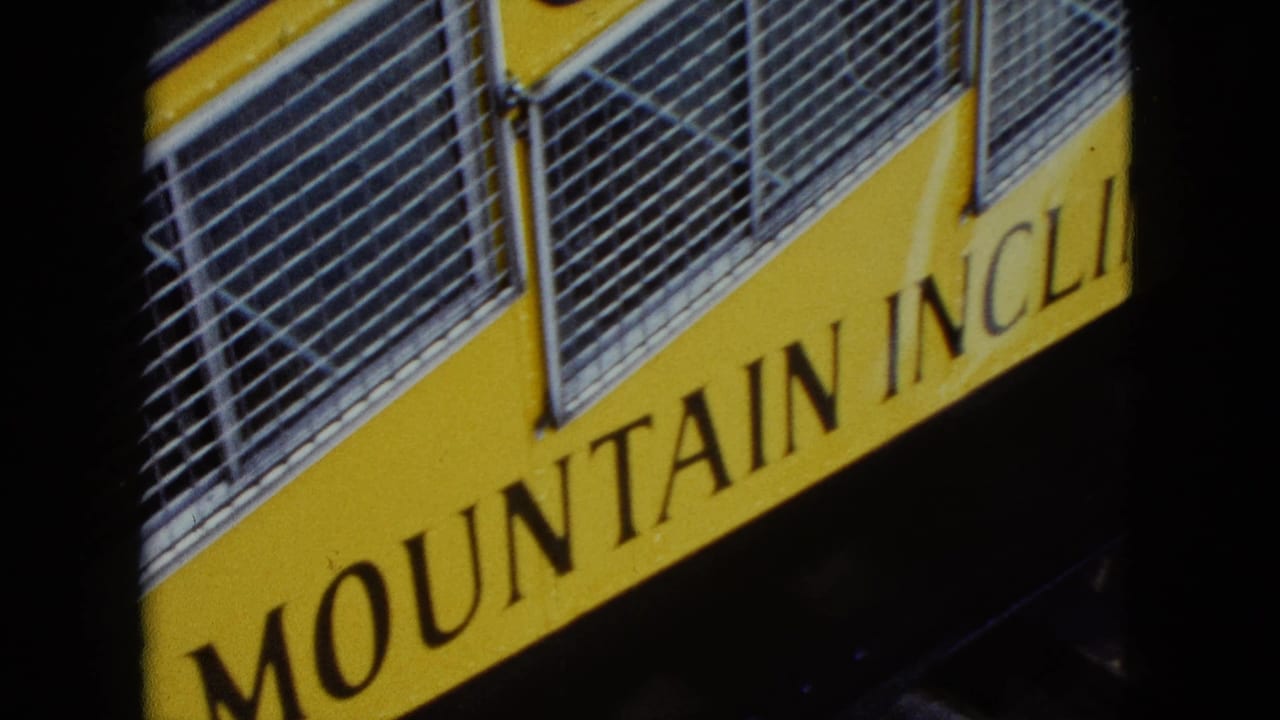 1959 Nevada 8mm frame showing the side of a yellow incline railway car with readable MOUNTAIN INCLINE lettering and barred windows.