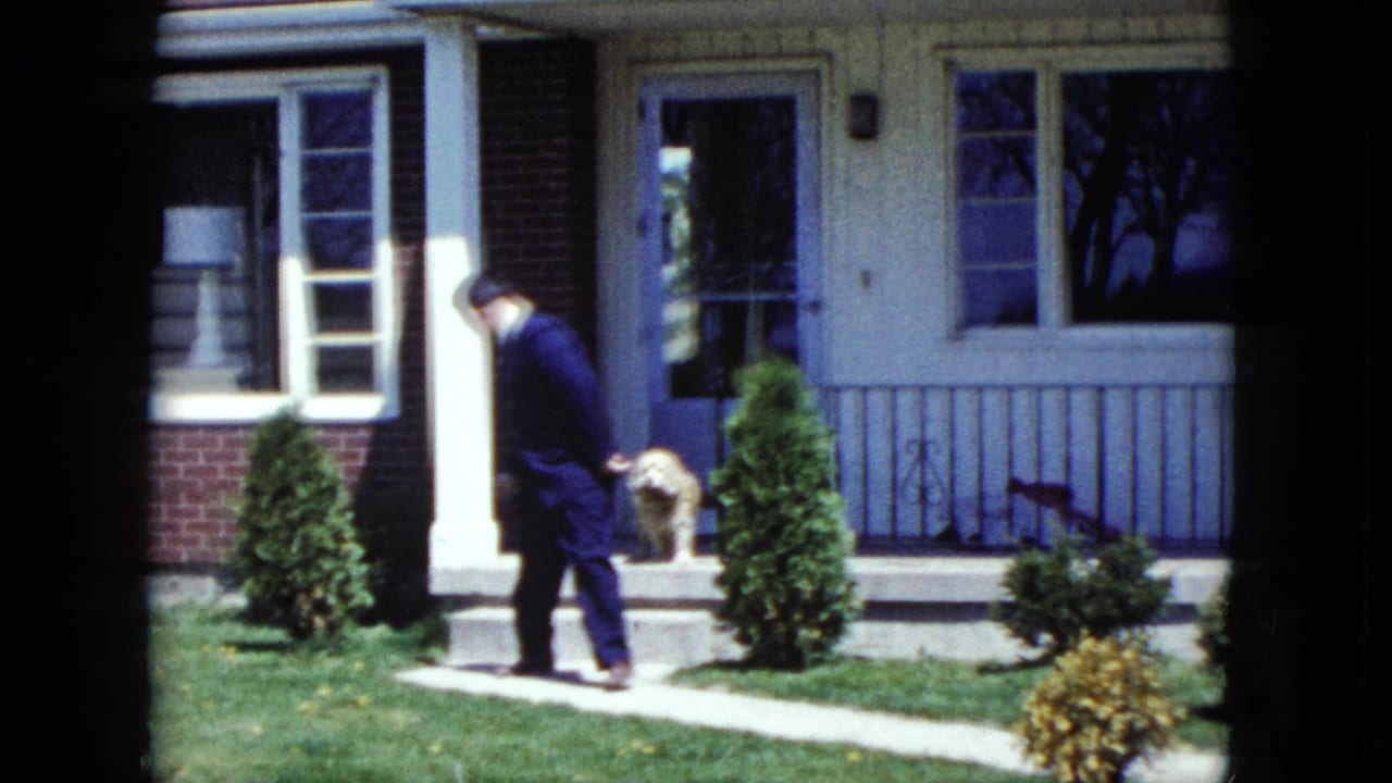 The suited man steps away from the porch of a Nevada suburban home in 1959 while a small dog stays by the open doorway.