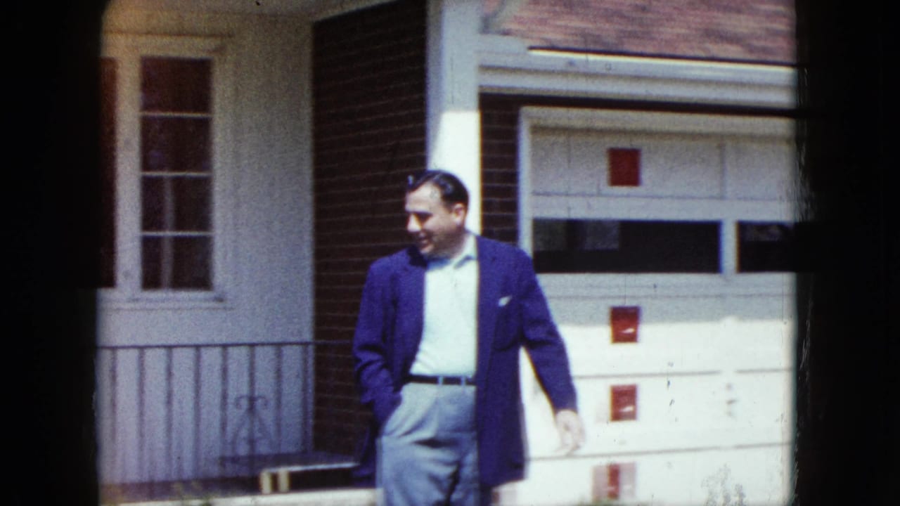 Man walking beside a garage door on a residential exterior.
