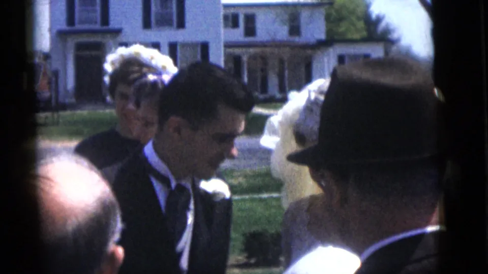The bride and groom appear among guests outside a Camden house, with formal clothing and hats visible in the 1960 wedding scene.