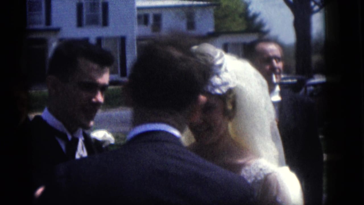 In 1960 Camden, New Jersey home-movie footage, a bride and groom stand close together during outdoor wedding vows.