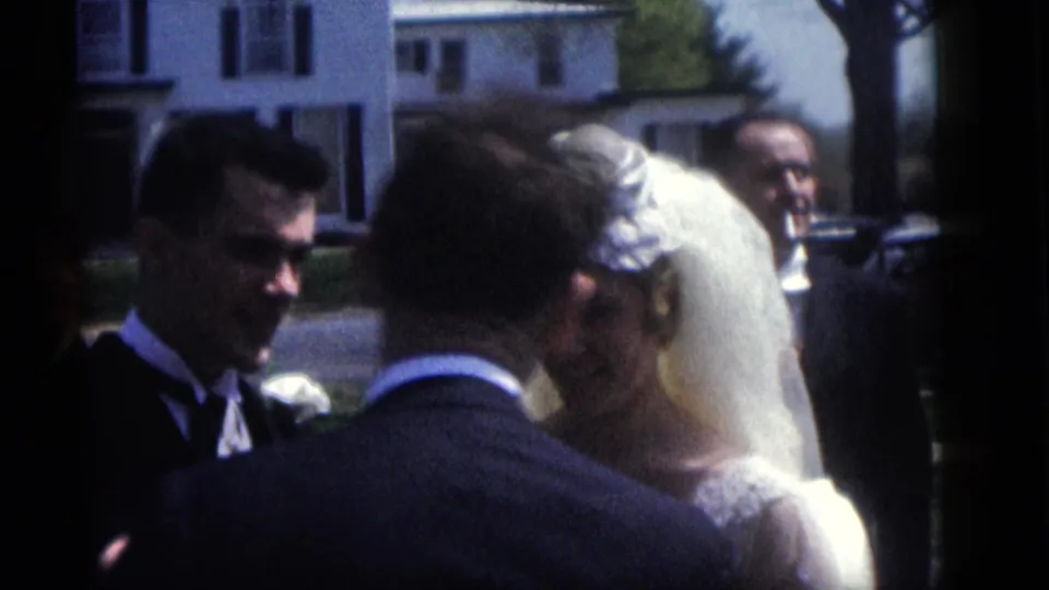 In 1960 Camden, New Jersey home-movie footage, a bride and groom stand close together during outdoor wedding vows.