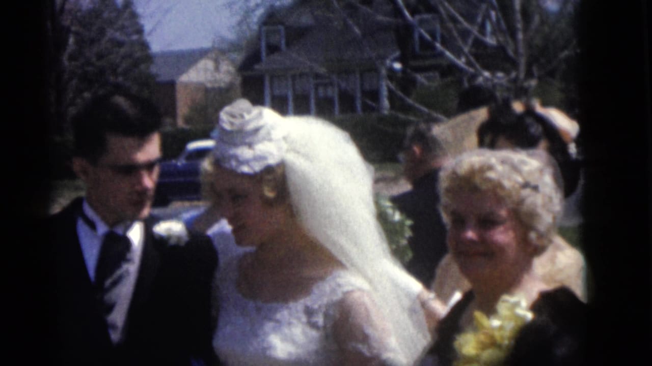 Close home-movie view of the bride, groom, and wedding guest outside in Camden, New Jersey in 1960.