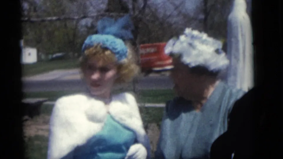Guests in period hats stand outdoors near the bride's trailing veil during the Camden, New Jersey wedding gathering.