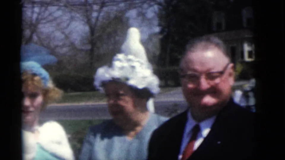 At the end of the 1960 Camden clip, the smiling couple stands near the white yard statue while another adult is partly visible at left.