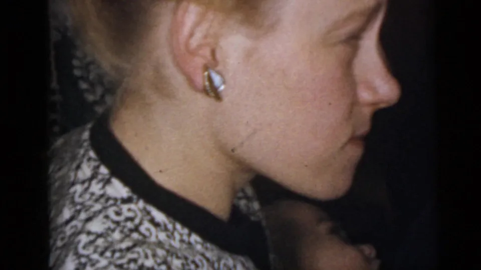 Close 1960 Camden home-movie view of a woman in profile, with earrings and a patterned garment visible in a private interior.