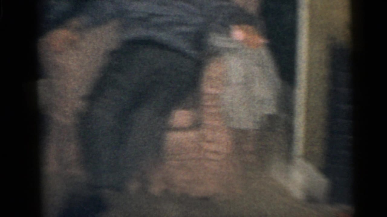 Soft, blurred interior shot with a seated adult figure partially visible near an armchair.