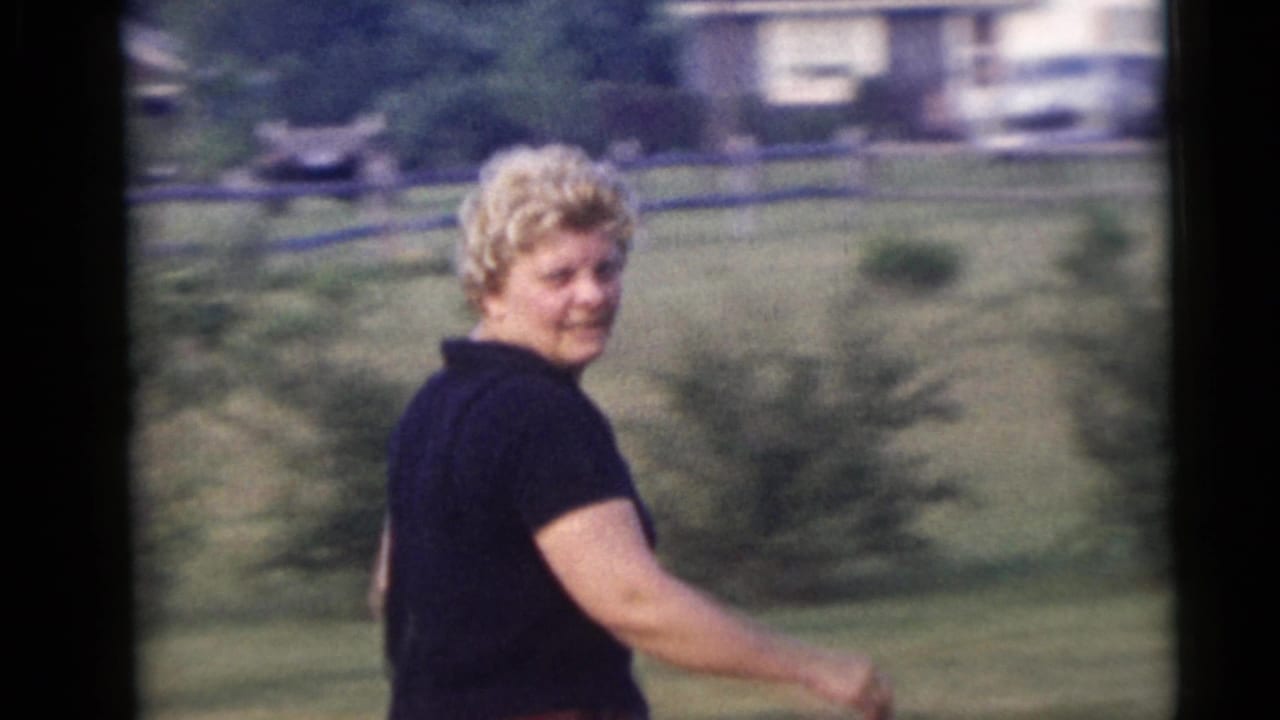 Woman turns toward the camera while walking in a grassy yard.