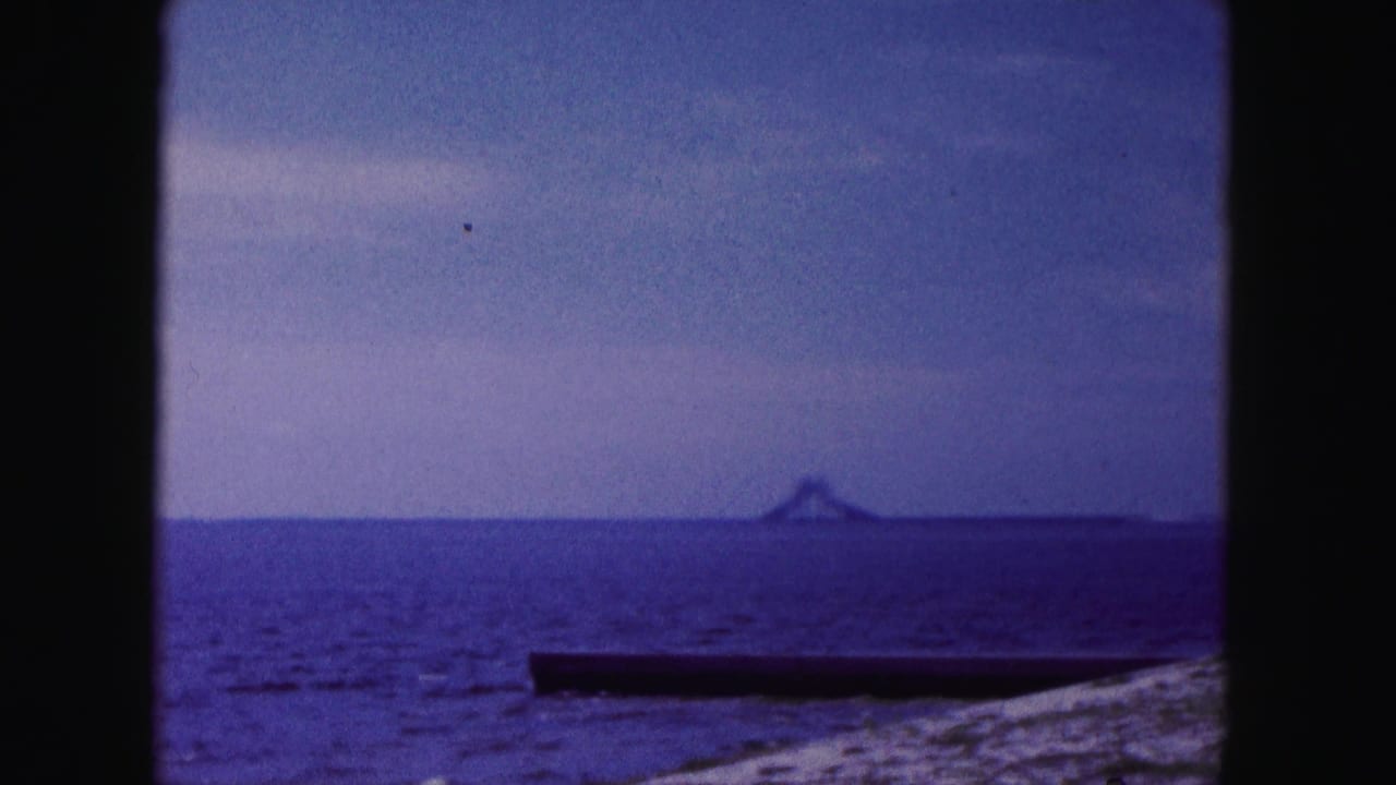 Open water beside a bridge with a distant tower-like structure on the horizon.