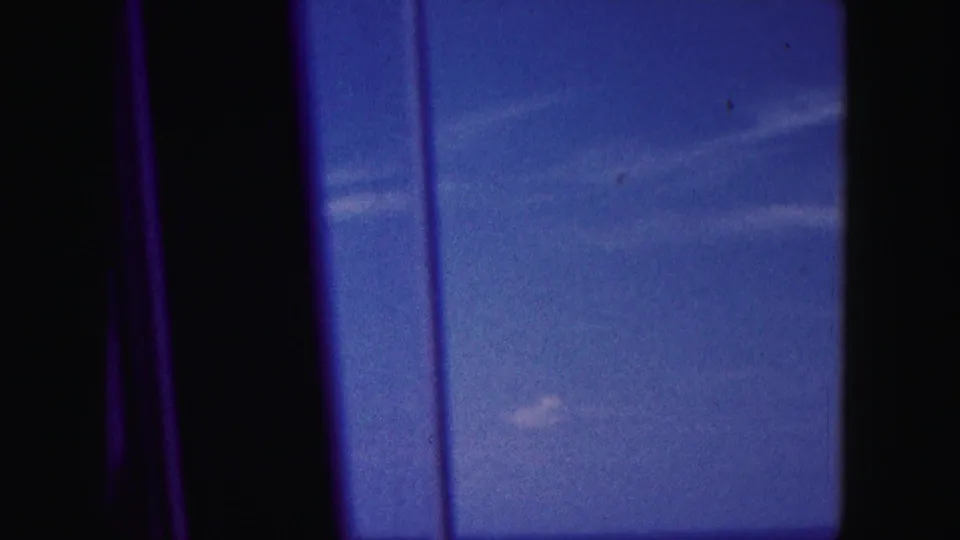 Soft 8mm frame from the Miami-area clip showing sky, water, and dark window framing during travel.