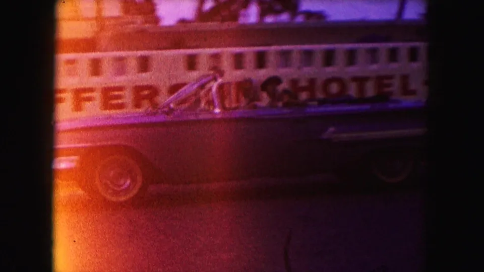 1960 Miami 8mm still showing the side of a classic convertible passing large hotel-motel lettering.